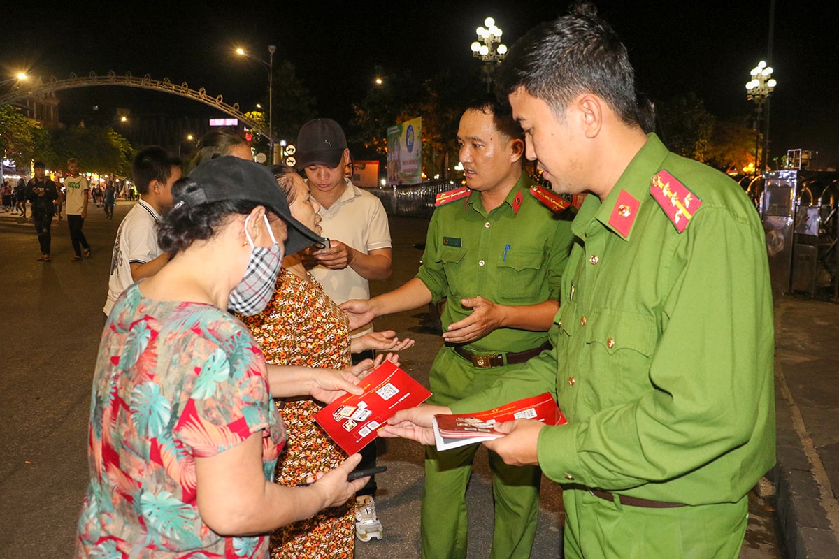 Cán bộ Phòng Cảnh sát Quản lý hành chính về trật tự xã hội Công an tỉnh phát tờ rơi, hướng dẫn người dân về quy trình đăng ký cài đặt định danh điện tử trên điện thoại.