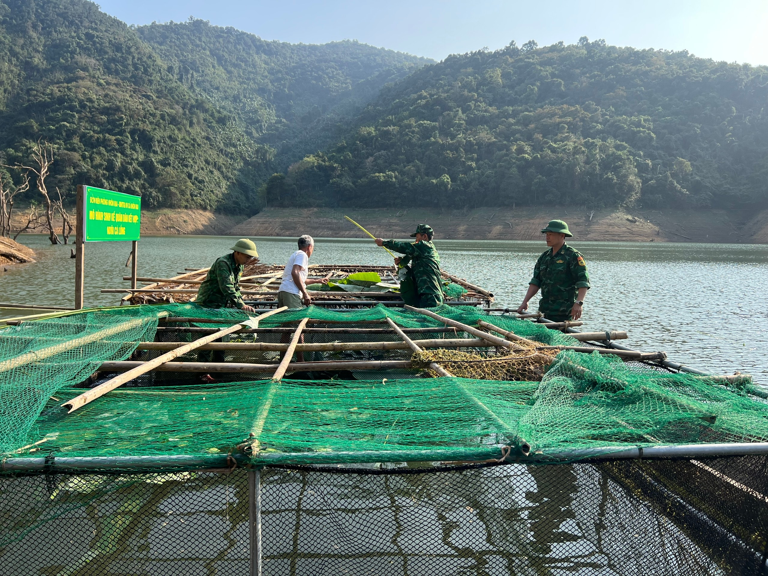 Đồn Biên phòng Nhôn Mai hướng dẫn người dân xây dựng mô hình sinh kế nuôi cá lồng trên sông. Ảnh: G.H