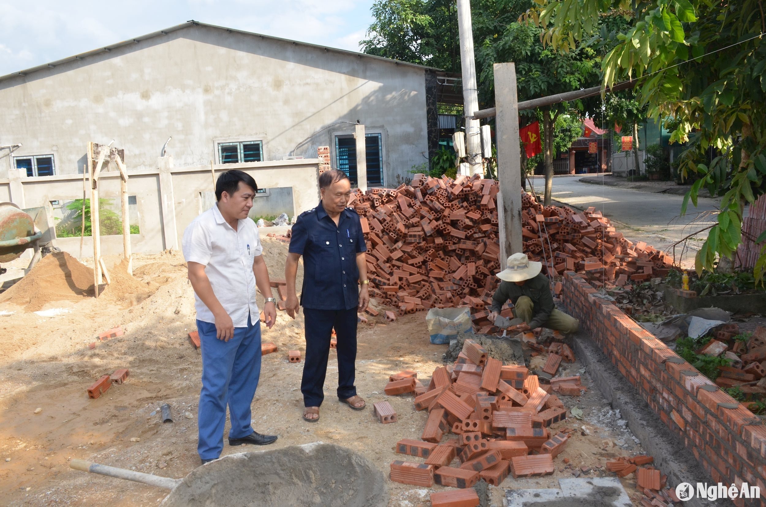 Ông Nguyễn Đình Sửu - Khối trưởng khối 3 cùng cán bộ thị trấn Tân Lạc (Quỳ Châu) kiểm tra việc thi công tường rào nhà văn hóa khối. Ảnh: Thành Chung