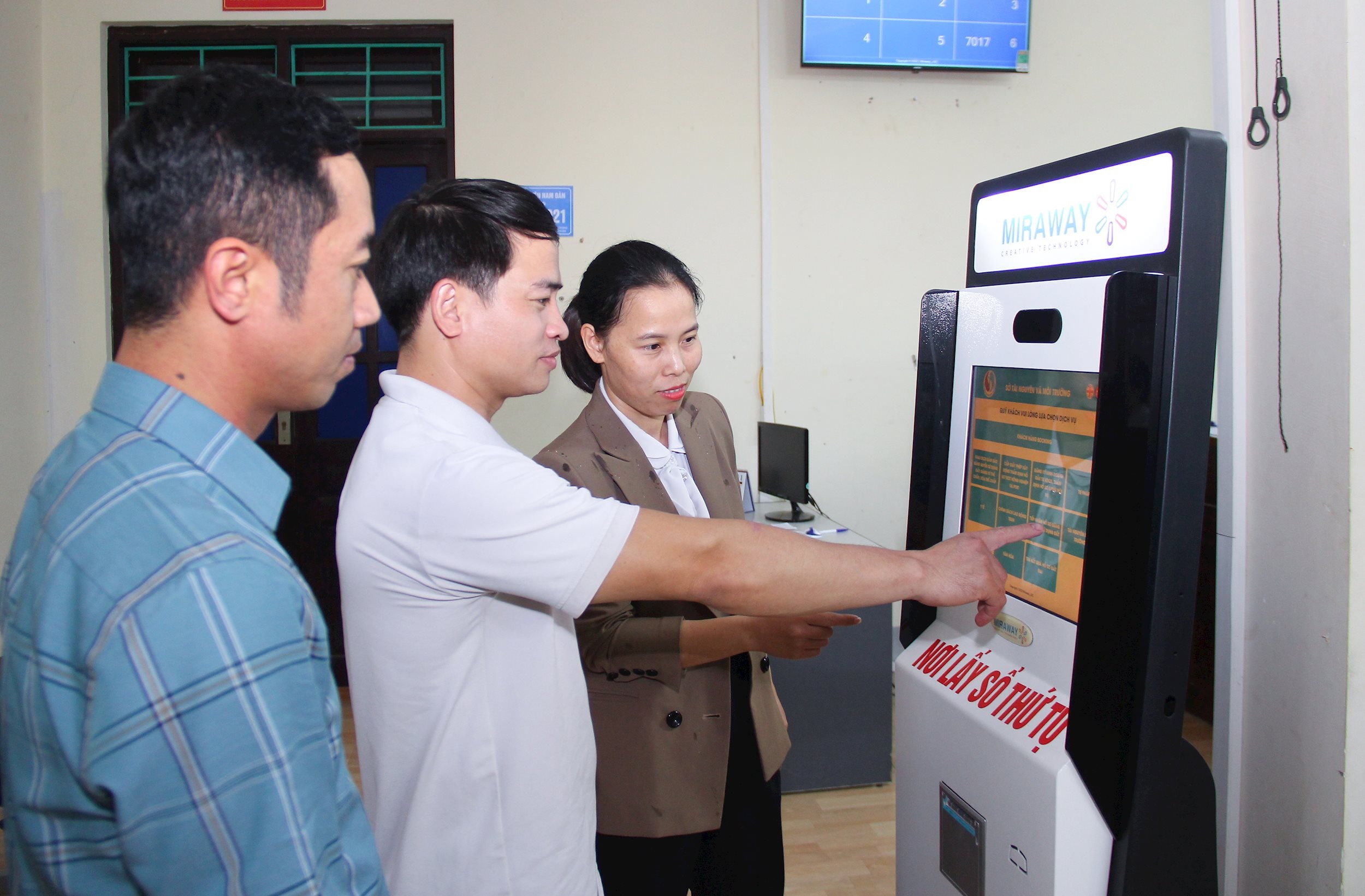 Cán bộ UBND huyện Nam Đàn hướng dẫn người dân bấm số thứ tự thực hiện giao dịch giải quyết thủ tục hành chính tại Bộ phận