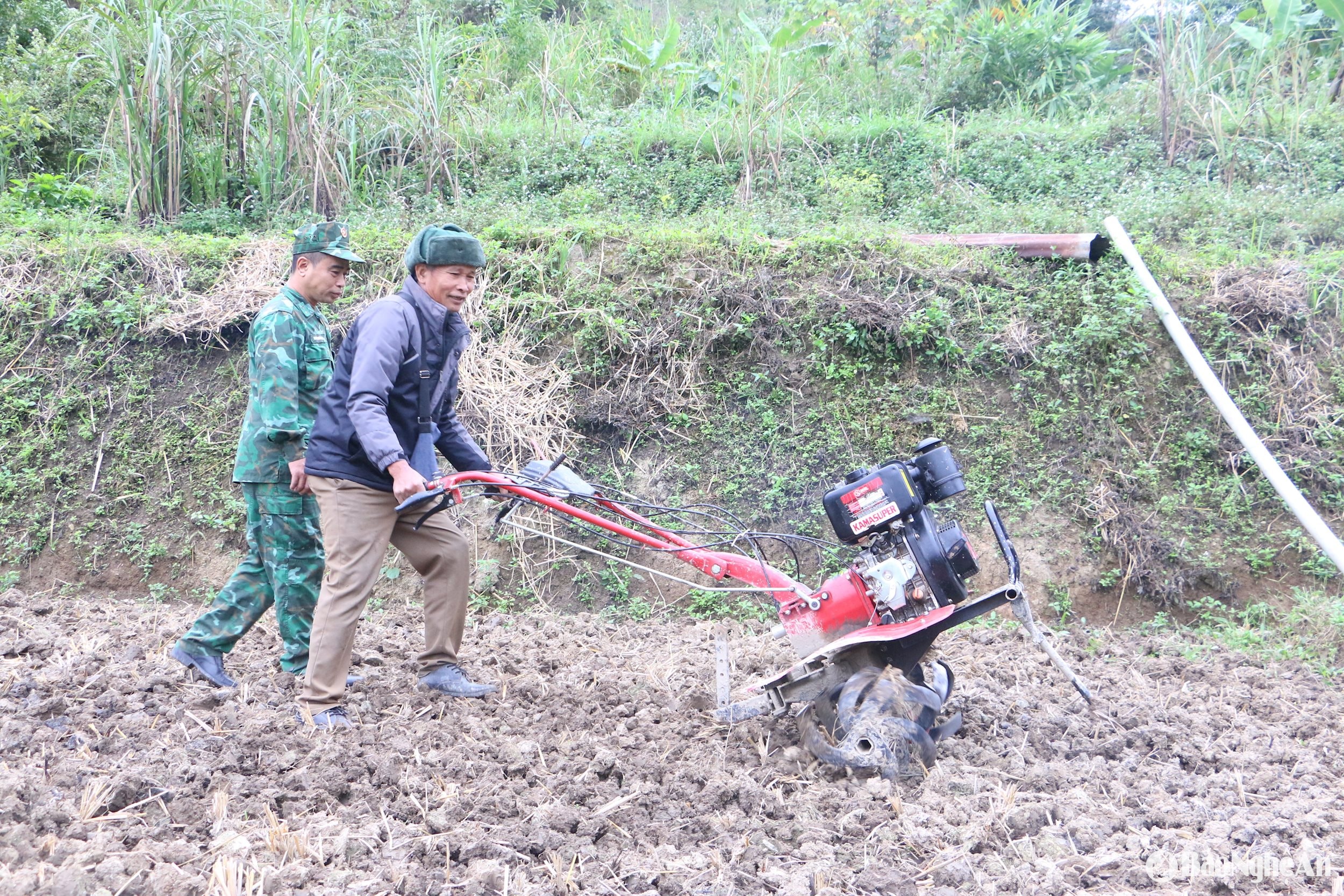 Cán bộ đồn biên phòng Nậm Càn giúp đỡ người dân sử dụng máy cày mi ni