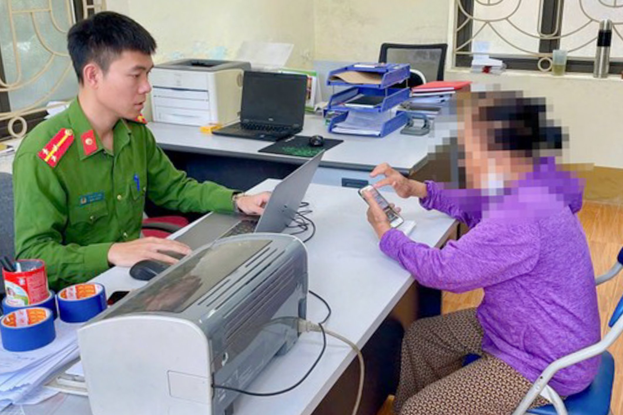Lực lượng chức năng giải thích cho bà L. về thủ đoạn giả danh công an để lừa đảo chiếm đoạt tài sản. (Ảnh: CACC)