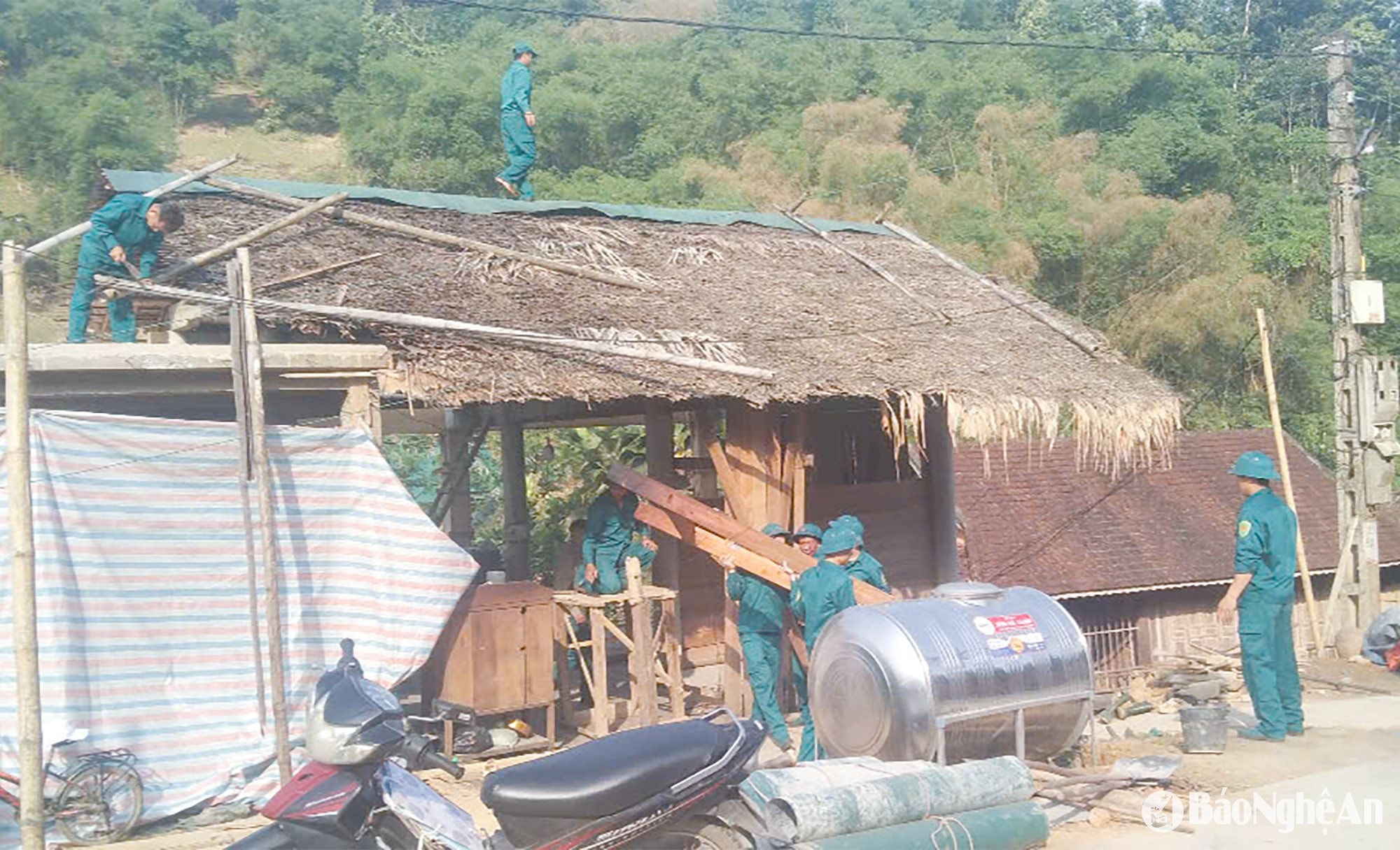 Lực lượng dân quân tự vệ xã Mậu Đức, huyện Con Cuông giúp dân dỡ nhà cũ để làm nhà ở mới