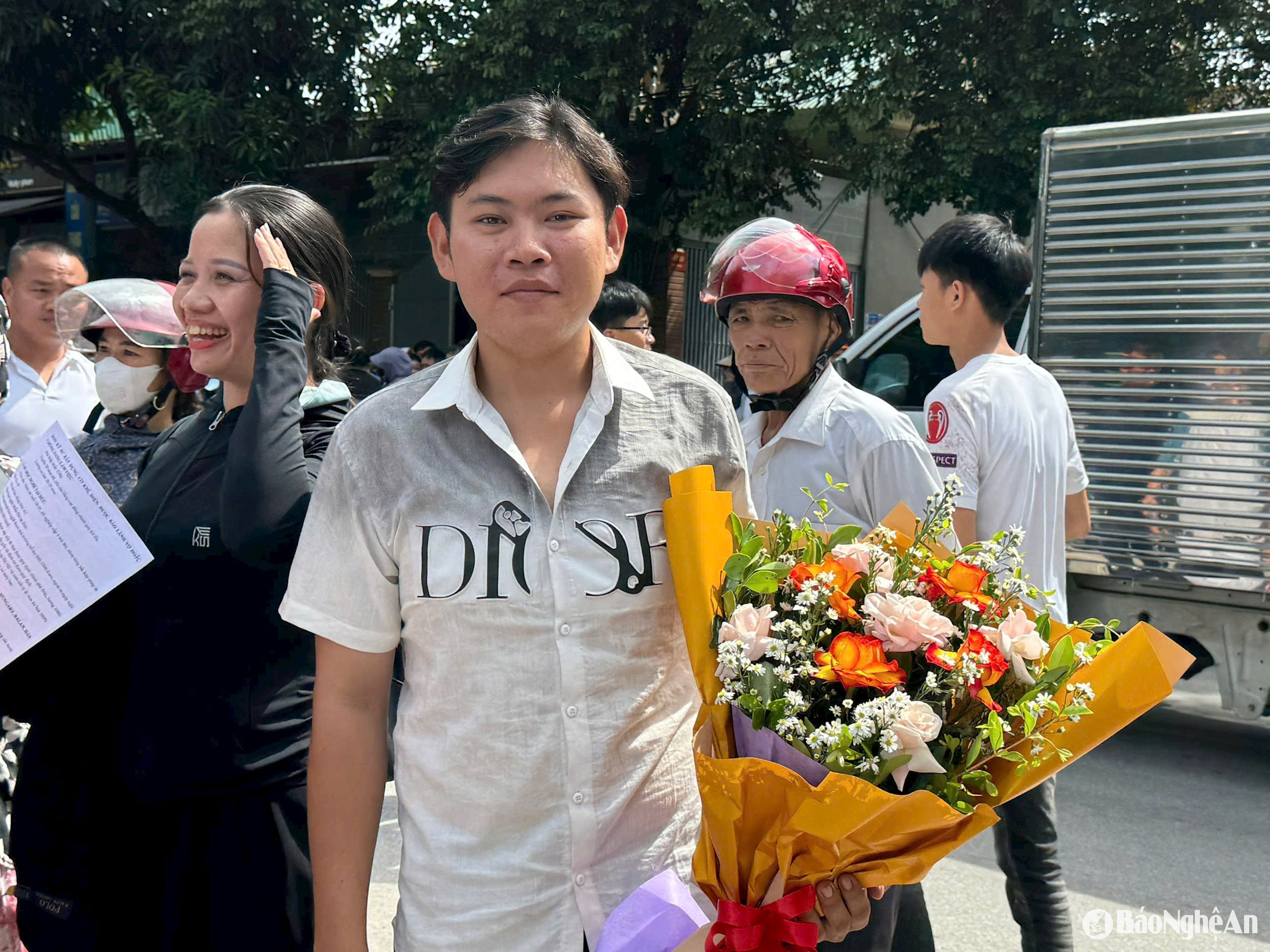 Phụ huynh ở điểm thi Trường THPT Đô Lương 1 cầm hoa để chúc mừng con hoàn thành Kỳ thi tốt nghiệp THPT