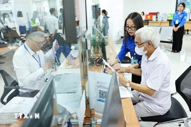 Đội thanh niên tình nguyện hỗ trợ vận hành chính quyền 2 cấp và cung cấp dịch vụ công trực tuyến tại Trung tâm Phục vụ hành chính công phường Cầu Giấy. (Ảnh: Minh Đức/TTXVN) ttxvn-mo-hinh-chinh-quyen-hai-cap-1307-2.jpg
