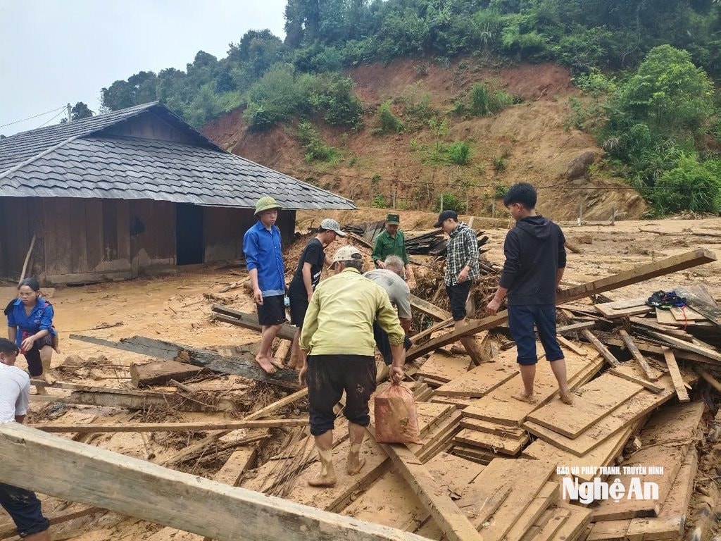 Người dân ở bản Huồi Mới giúp nhau soạn lại đồ đạc bị lũ vùi lấp nhà. Ảnh: VT