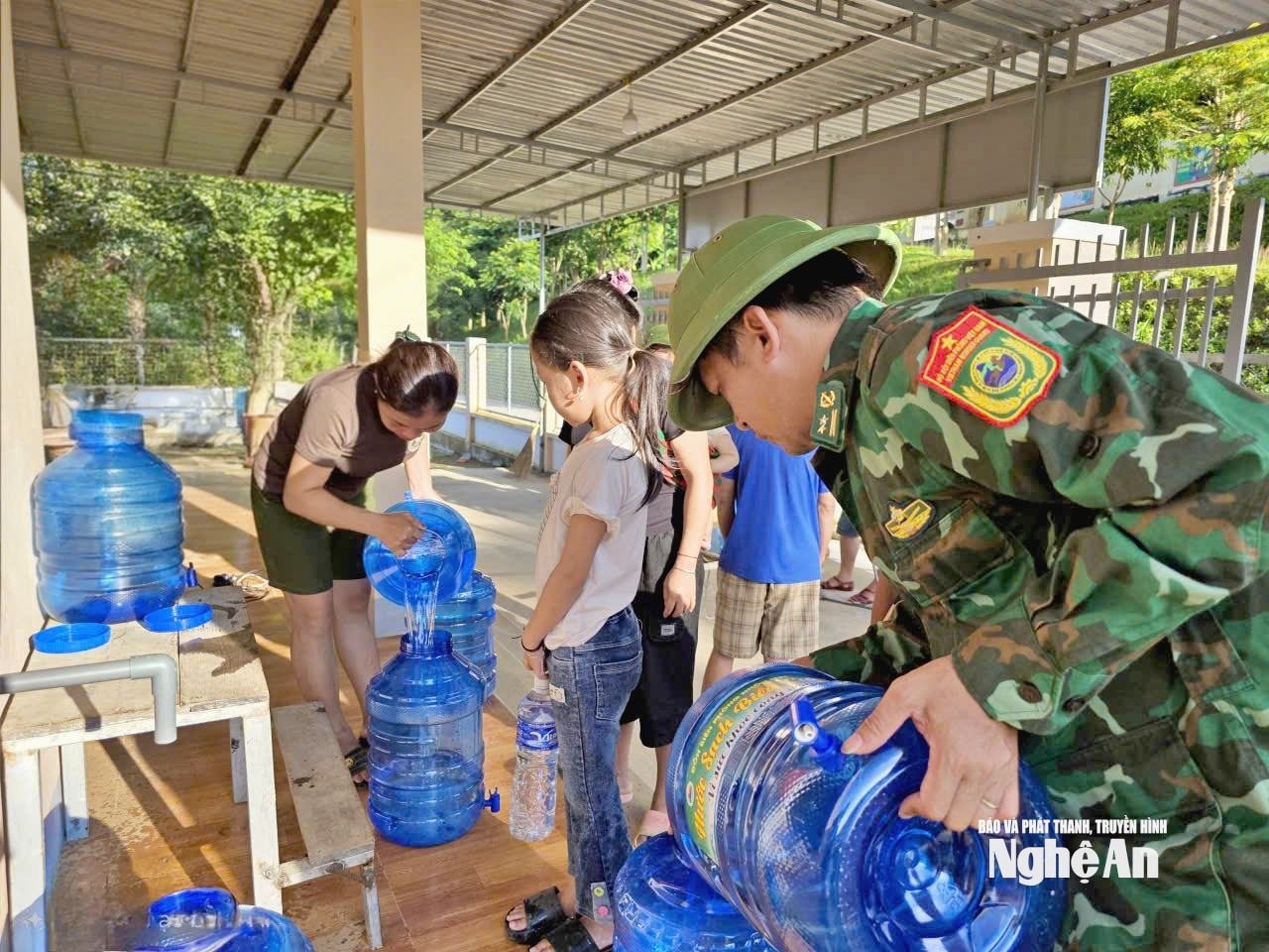 Cán bộ Đồn Biên phòng Nhonn Mai hỗ trợ người dân lấy nước tại Ngôi nhà thiện nguyện Sao Xanh