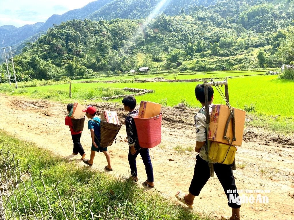 Trẻ em người Mông ở bản Huồi Mới cõng hàng nhu yếu phẩm của đoàn thiện nguyện trao tặngvượt núi về bản, mất khoảng 10 tiếng đồng hồ đi bộ do đường sạt lở, chia cắt nghiêm trọng. Ảnh: Văn Trường.