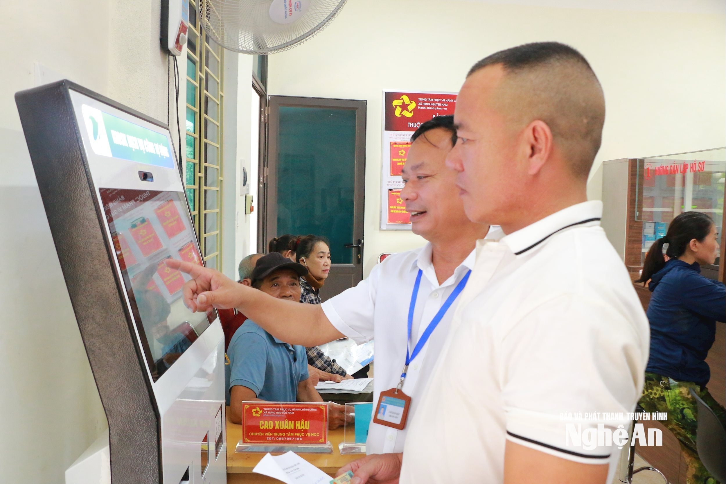 Cán bộ Trung tâm Dịch vụ hành chính công xã Hưng Nguyên Nam hướng dẫn người dân sử dụng dịch vụ công. Ảnh Khánh Ly