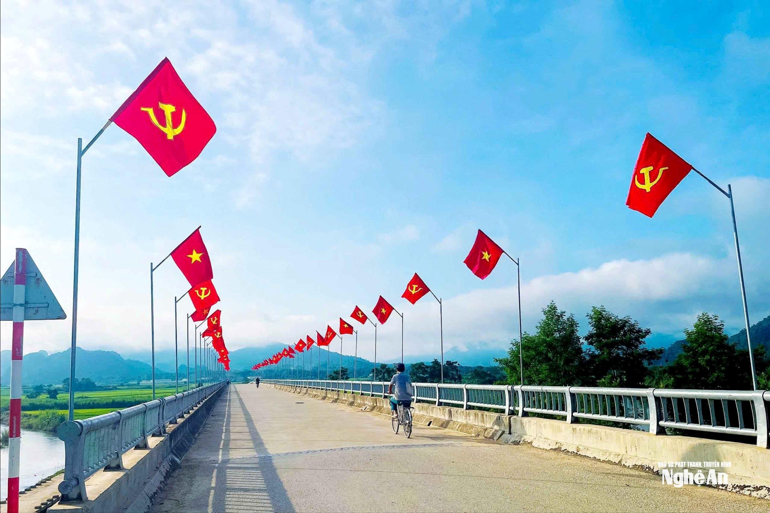 Trên đoạn cầu Sông Hạt, bản Hoa Tiến, xã Châu Tiến, những lá cờ đỏ thắm tung bay rực rỡ. Toàn xã Châu Tiến đã cắm hơn 5.000 lá cờ dọc các tuyến đường, tạo nên cảnh quan rực rỡ, thu hút ánh nhìn của du khách khi qua đây. Ảnh: Thanh Quỳnh