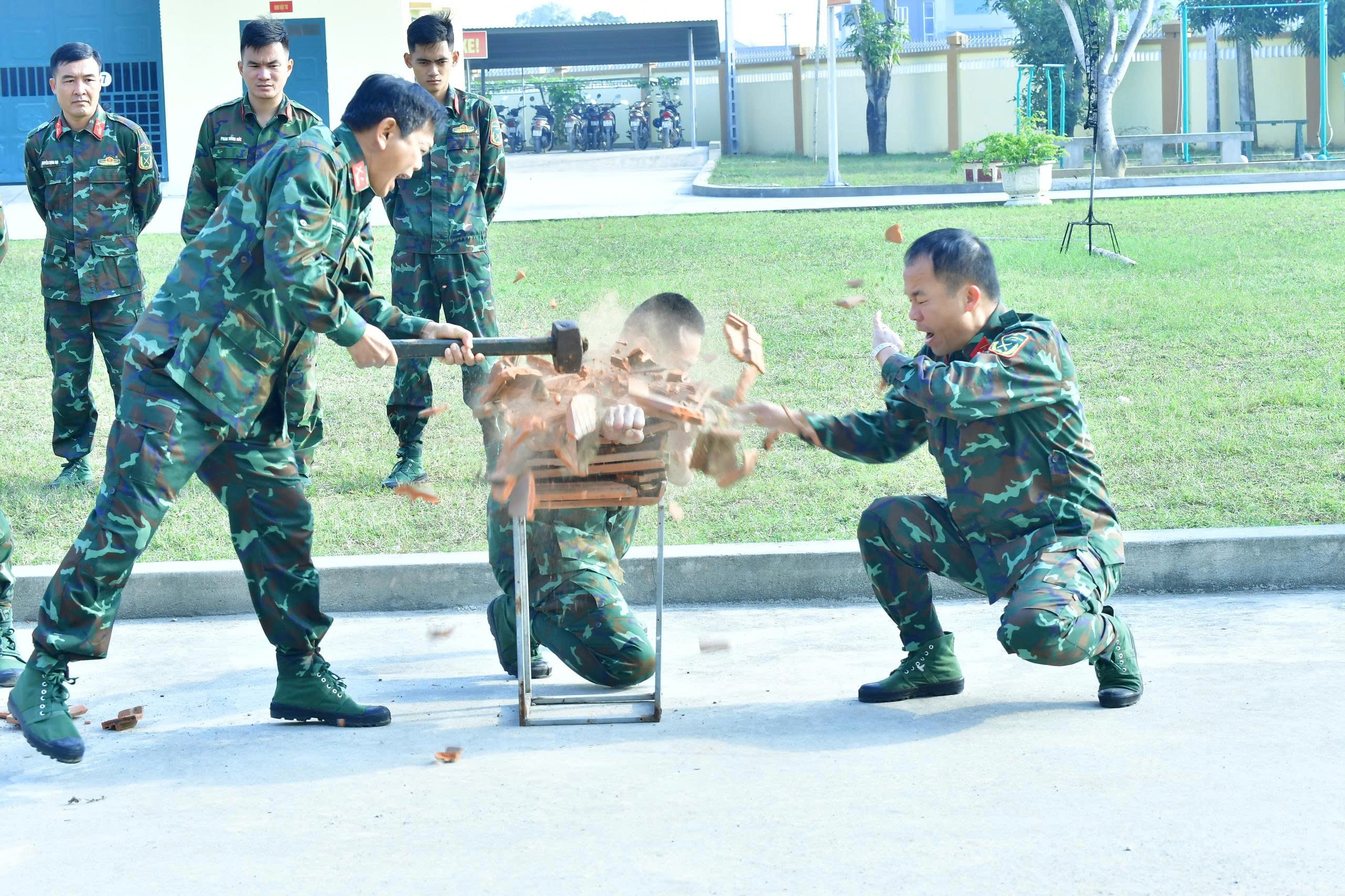 Nhờ chăm chỉ khổ luyện mà cánh tay chiến sĩ trinh sát có thể nằm giữa 10 lớp ngói và chịu được lực đập của búa sắt. Ảnh Trọng Kiên