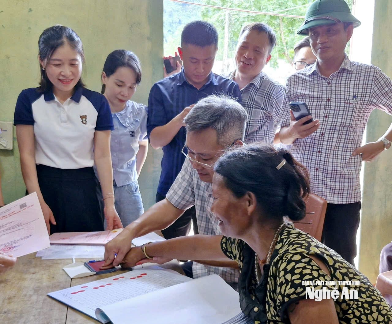 Cán bộ Văn phòng Dăng ký đất đai tỉnh Nghệ An giúp đồng bào Đan Lai điểm chỉ, nhận giấy đăng ký quyền sử dụng đất. Ảnh: Nhật Lân