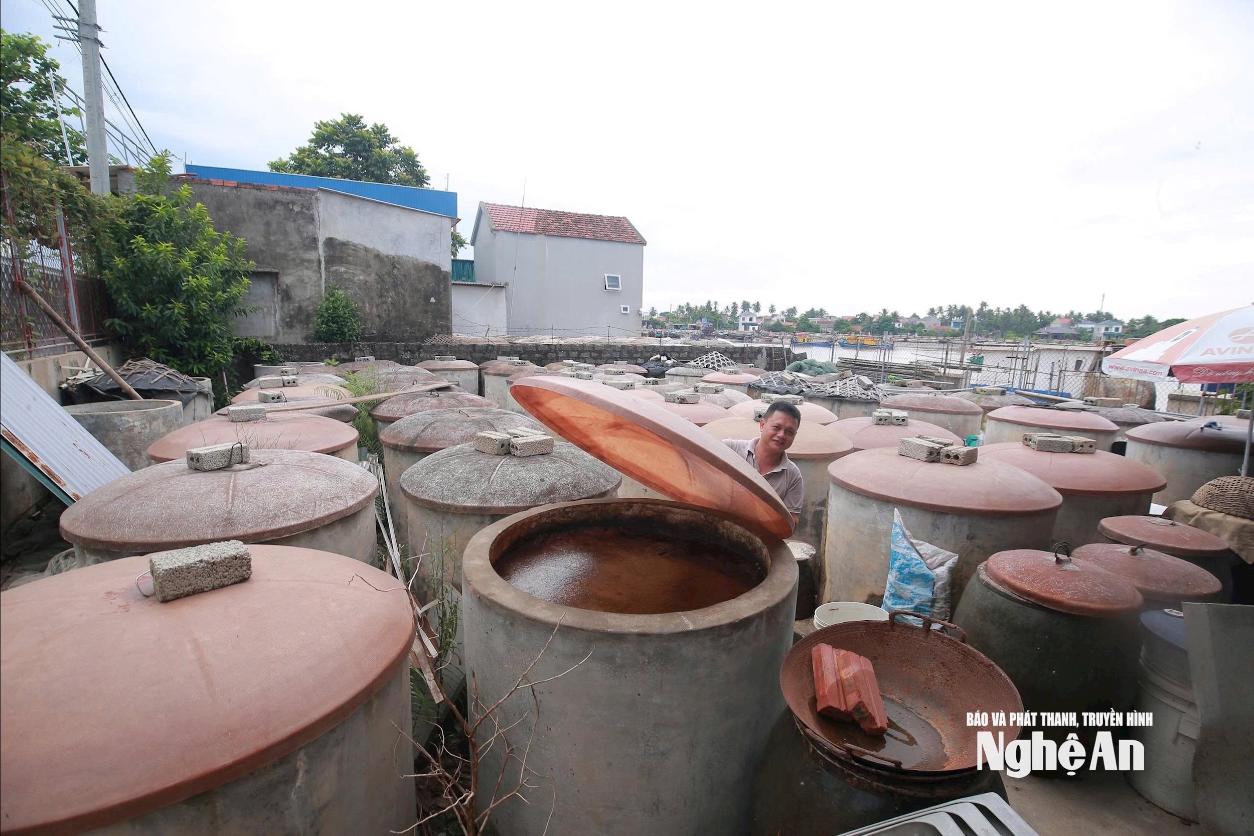 Các hộ dân làng nghề nước mắm Quỳnh Mai, Tân Mai che chắn, dằn chèn các thùng nước mắm, mắm tôm để phòng gió lốc, mưa lớn. Ảnh: T.P