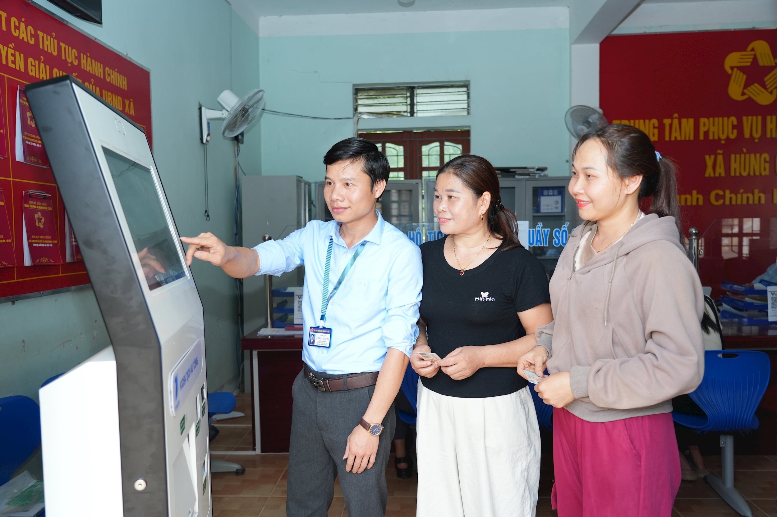 Cán bộ xã Hùng Chân hướng dẫn người dân lấy số thứ tự khi đến làm thủ tục hành chính