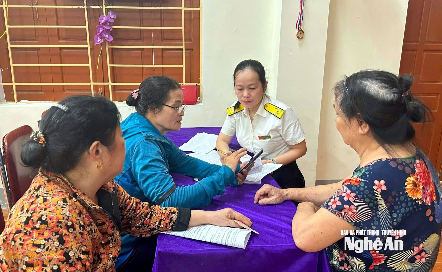 Cán bộ Chi cục Thuế TP. Vinh hướng dẫn người dân sử dụng ứng dụng thuế. Ảnh Quang An