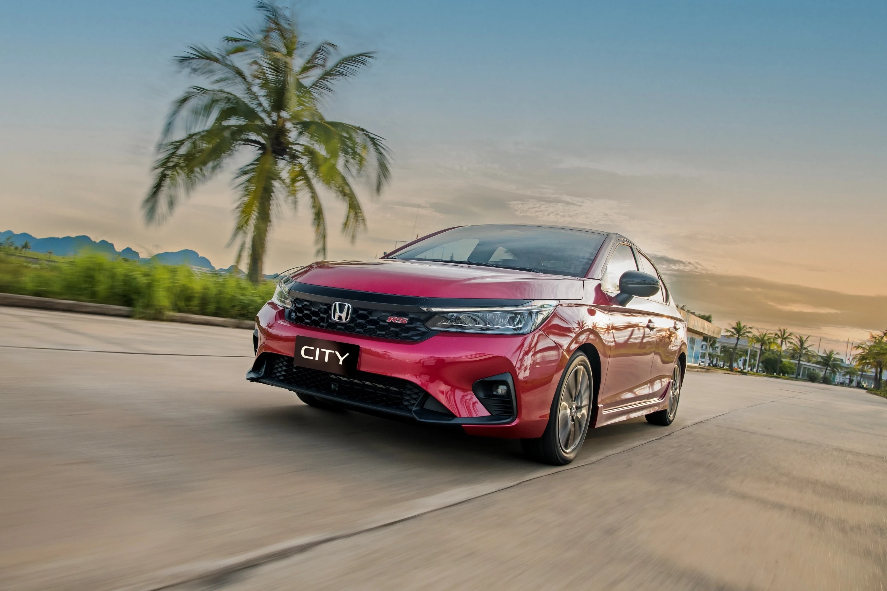Honda City màu đỏ đang vận hành trên đường phố.