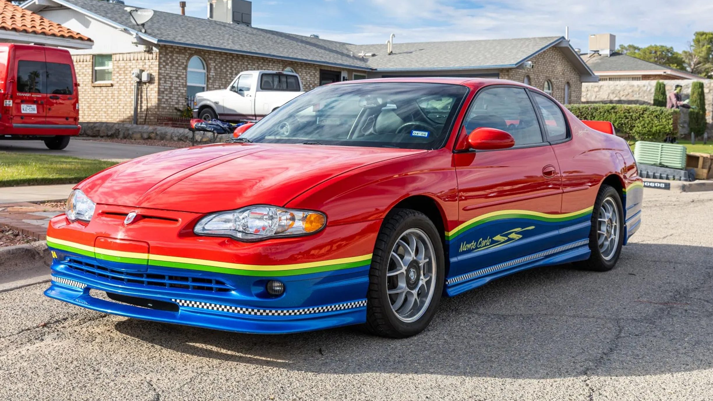 Góc trước 3/4 của coupe đỏ, khe thoát gió nắp ca-pô, sọc đa sắc, mâm lưới.