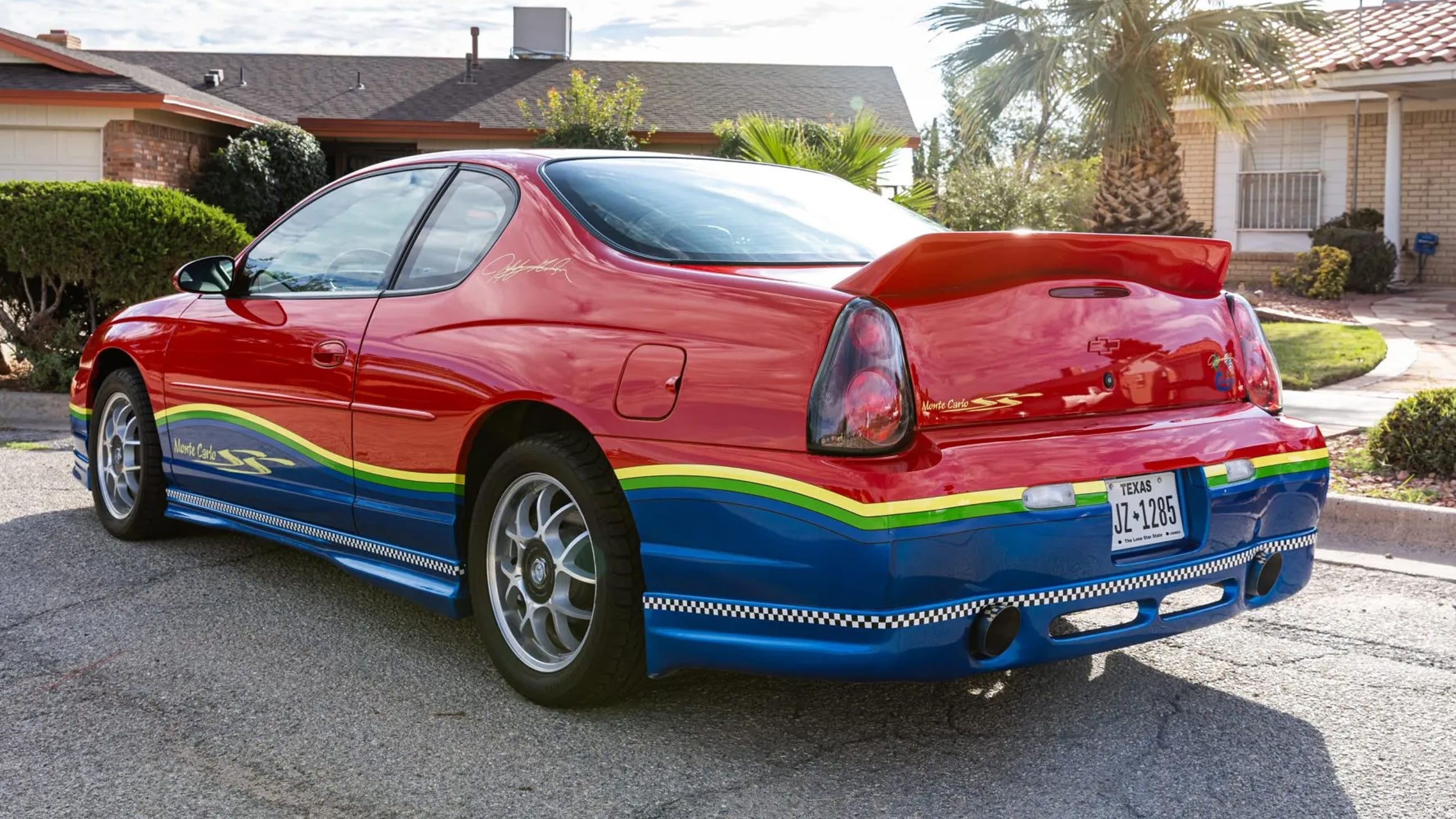 Góc sau 3/4, thân dưới xanh, sọc đa sắc, cánh gió, biển số Texas.