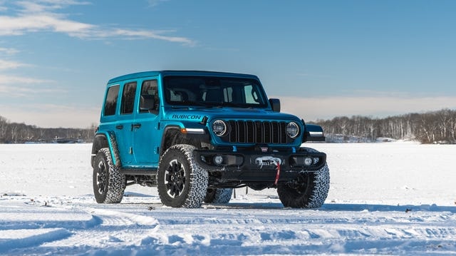 front three quarter view of blue suv parked on snowy landscape under clear blue sky.