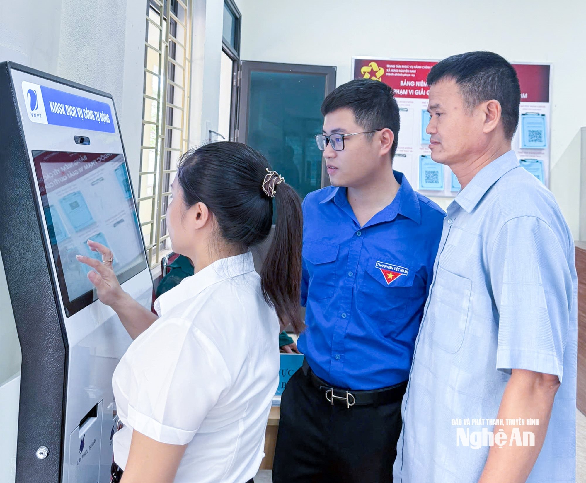 Công chức xã Hưng Nguyên Nam hướng dẫn người dân sử dụng hệ thống dịch vụ công tự động. Ảnh Mai Hoa