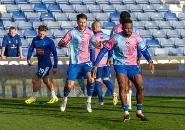 Các cầu thủ Oldham tập luyện trong trang phục màu hồng và xanh của Angels United.