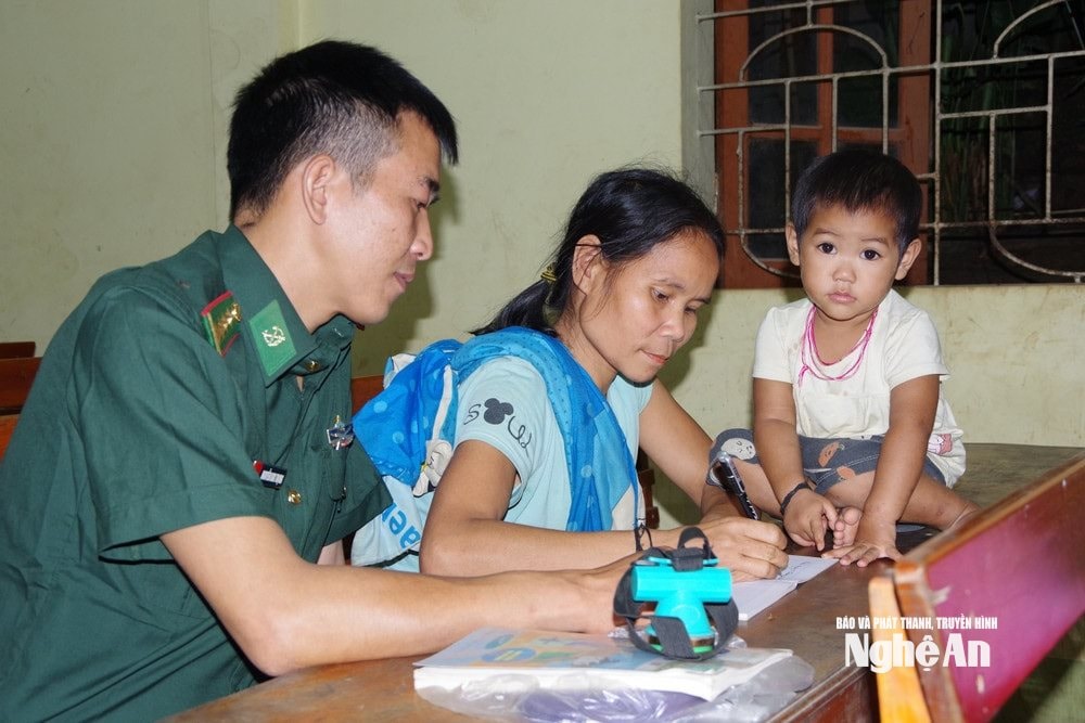 Đại uý Nguyễn Kim Trọng hướng dẫn người dân bản Phồng xã Tam Hợp viết chữ. Ảnh LT