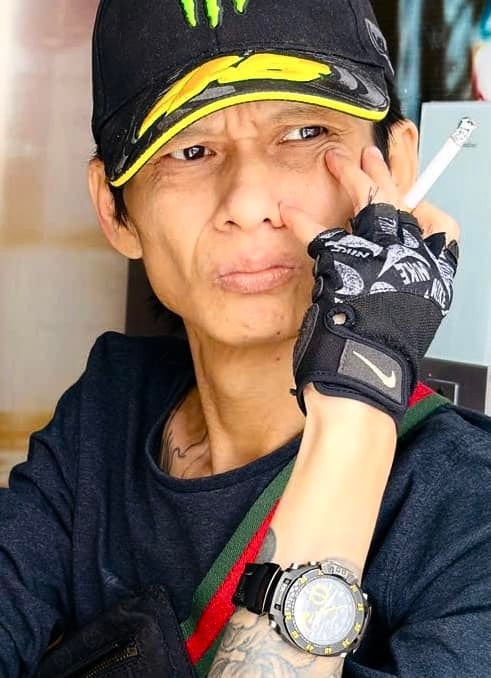 Nhiếp ảnh gia Lân Trần ngồi trên xe lăn và cầm máy ảnh, gương mặt thể hiện sự tập trung.