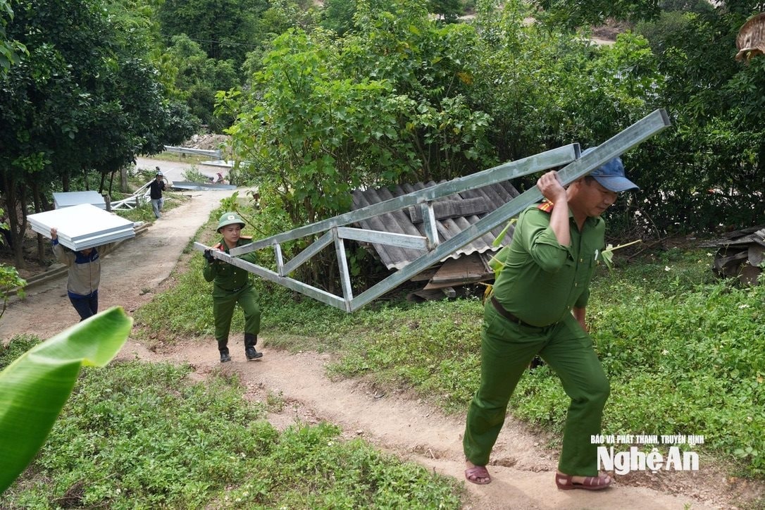 Các lực lượng công an xã Mường Típ cõng vật tư làm nhà cho bà con sau lũ. Ảnh Văn Trường