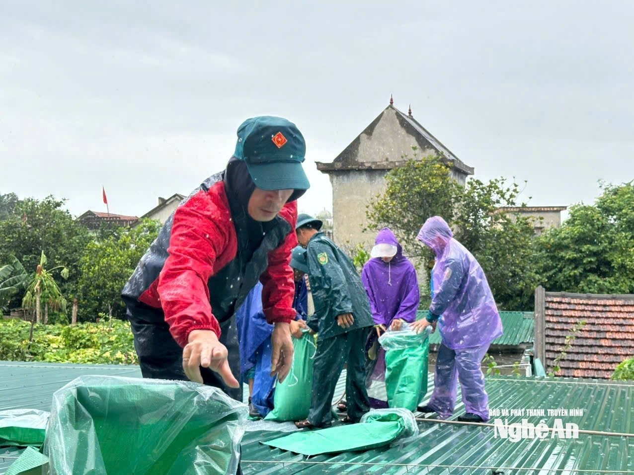 Các lực lượng giúp người dân phường Tân Mai gia cố mái nhà phòng chống mưa bão vào chiều 21-7. Ảnh Hoài Thu