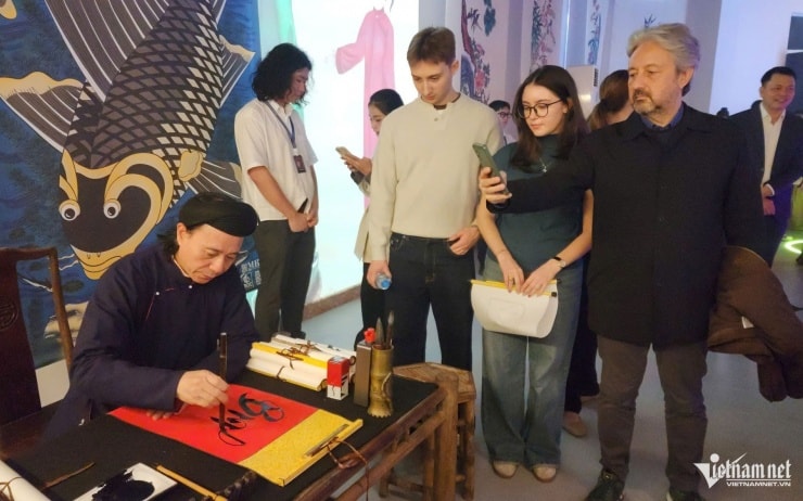 Khách du lịch quốc tế tìm hiểu về tranh Hàng Trống tại triển lãm.