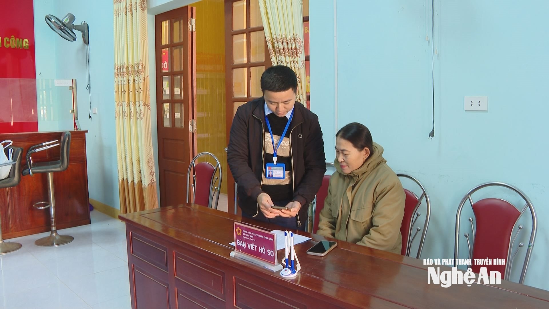 Bà Lữ Thị Mười ở bản Khe Tằm, xã Châu Bình được cán bộ xã hướng dẫn thực hiện nộp hồ sơ trực tuyến. Ảnh: Sỹ Đạt