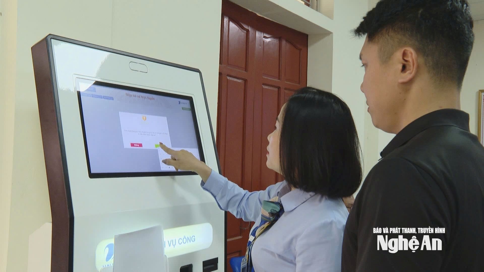 Cán bộ Trung tâm Phục vụ Hành chính công của phường Vinh Phú hướng dẫn, hỗ trợ người dân nộp hồ sơ trực tuyến. Ảnh: Hữu Song