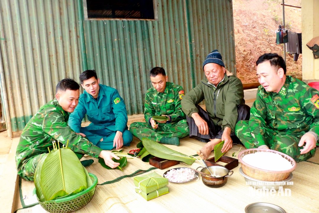 ông Xồng Xìa Lỳ ( đội mũ) -người uy tín bản Huồi Mới gói bánh chưng cùng cán bộ tổ công tác biên phòng Huồi Mới. Ảnh KL