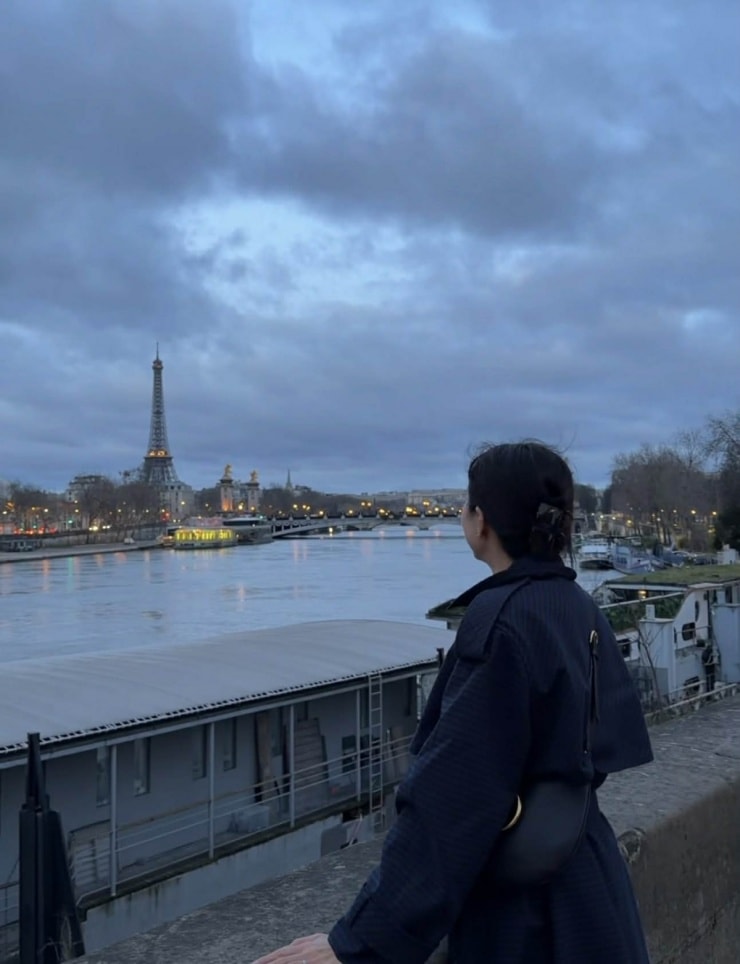 Bà mẹ ba con dạo bộ dọc theo sông Seine, ngắm thành phố Paris lúc trời vừa hửng sáng, khi đèn đường vẫn còn rọi vàng trên mặt nước.