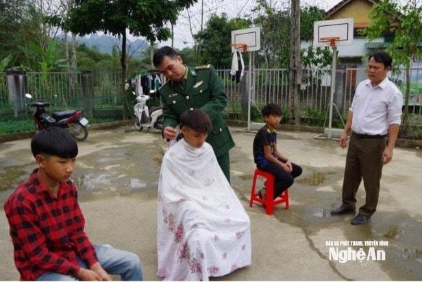 Trung tá Phan Văn Thắm cắt tóc cho học sinh Đan Lai. Ảnh KL