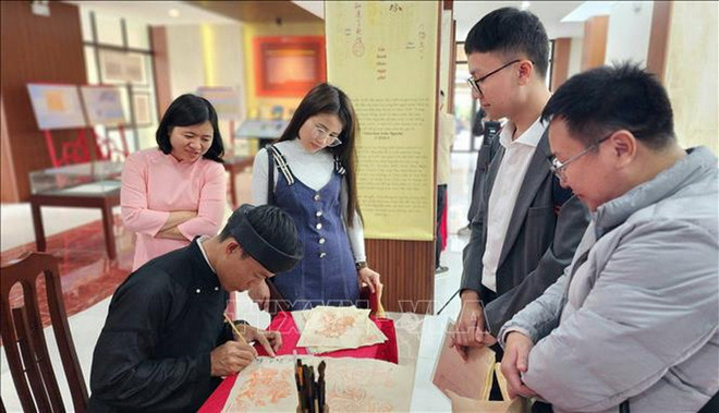 Đông đảo du khách chờ được tặng chữ thư pháp đầu xuân. (Ảnh: Chu Thanh Vân/TTXVN) 1.jpg