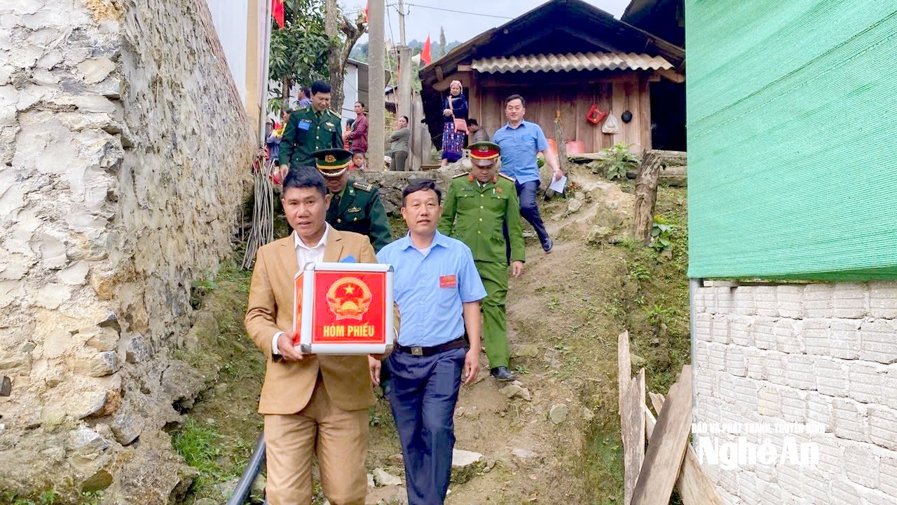 Cán bộ các Tổ bầu cử của xã Nậm Cắn mang hòm phiếu phụ đến từng nhà cử tri cao tuổi, sức khỏe yếu trong sáng 15-3. Ảnh PV