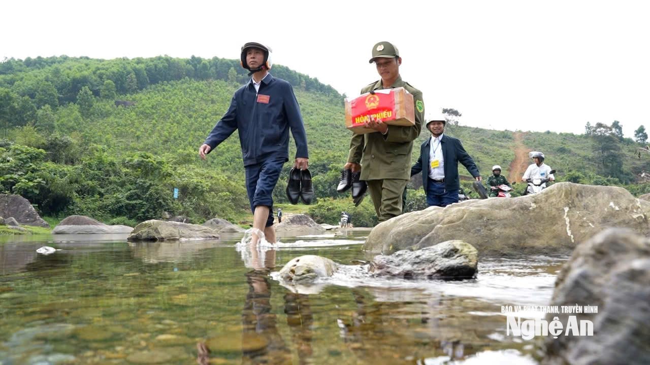 Lực lượng chức năng mang thùng phiếu phụ vượt khe suối đến các bản làng vùng sâu, vùng xa. Ảnh P.V