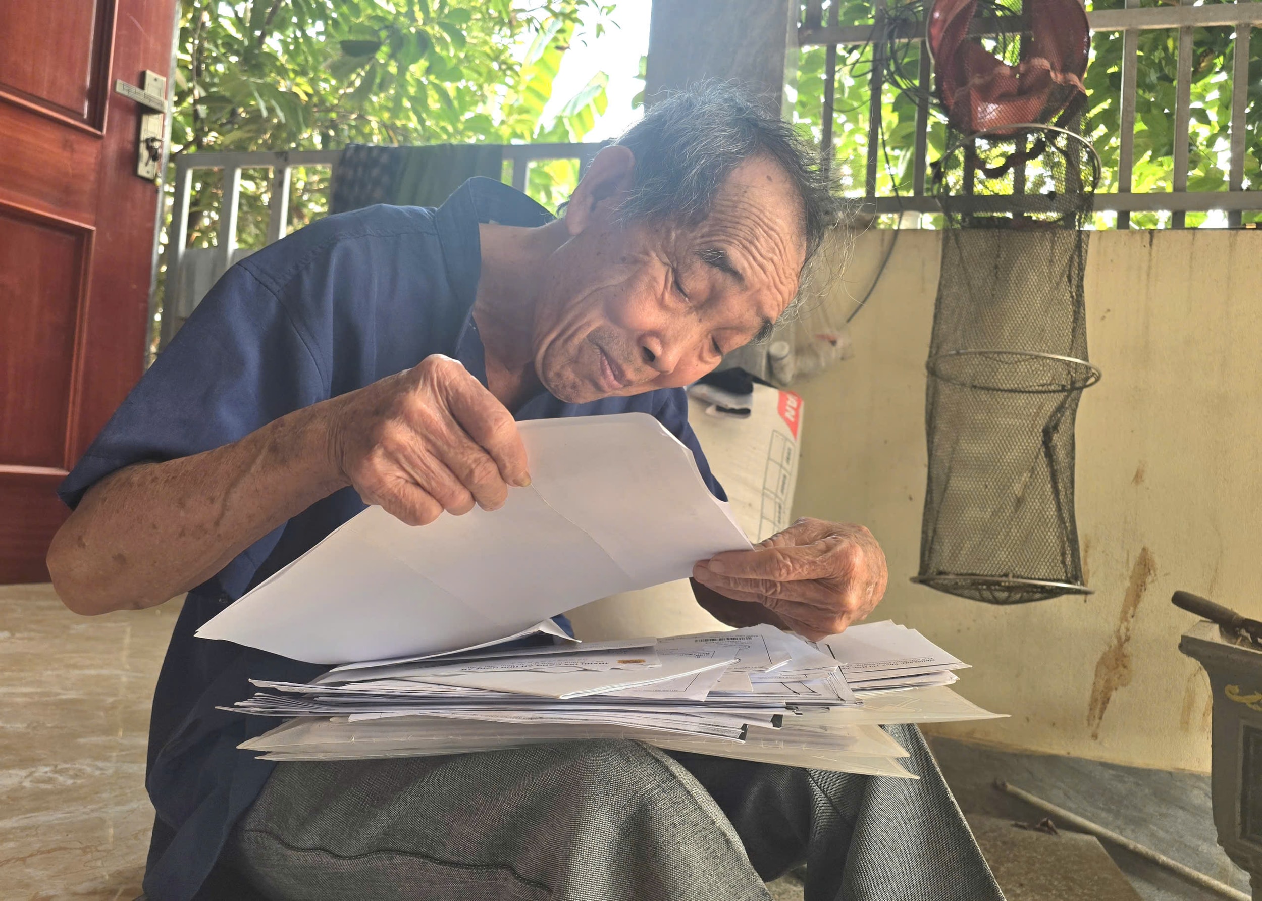 Ông Chính cầm trên tay đống hồ sơ, kiên trì theo đuổi vụ kiện để đòi lại tiền phường. Ảnh: Tiến Hùng