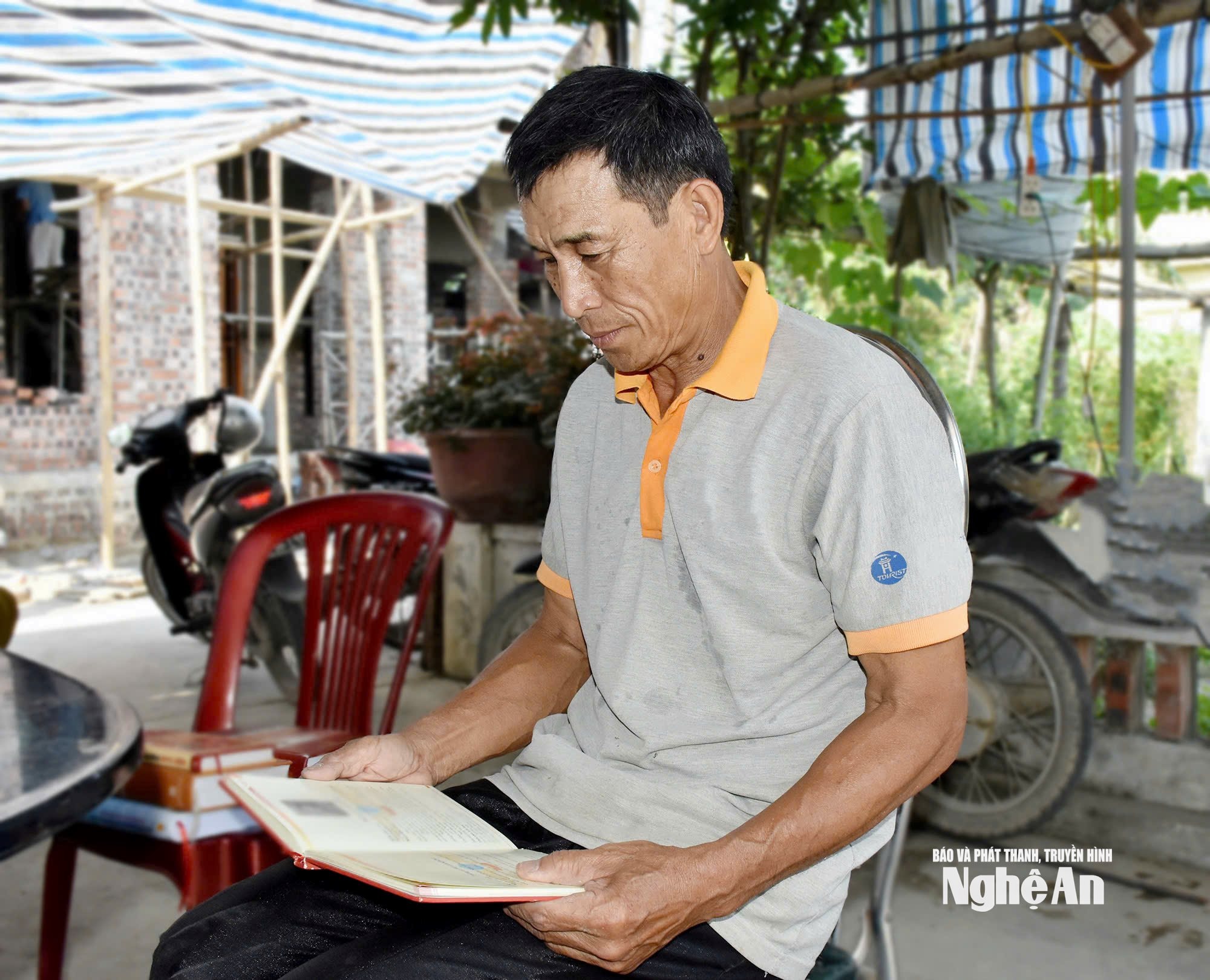 Ông Ngô Đức Phượng xem lại tư liệu về chiến công của anh trai - Anh hùng, liệt sĩ Ngô Đức Mai. Ảnh: Công Kiên