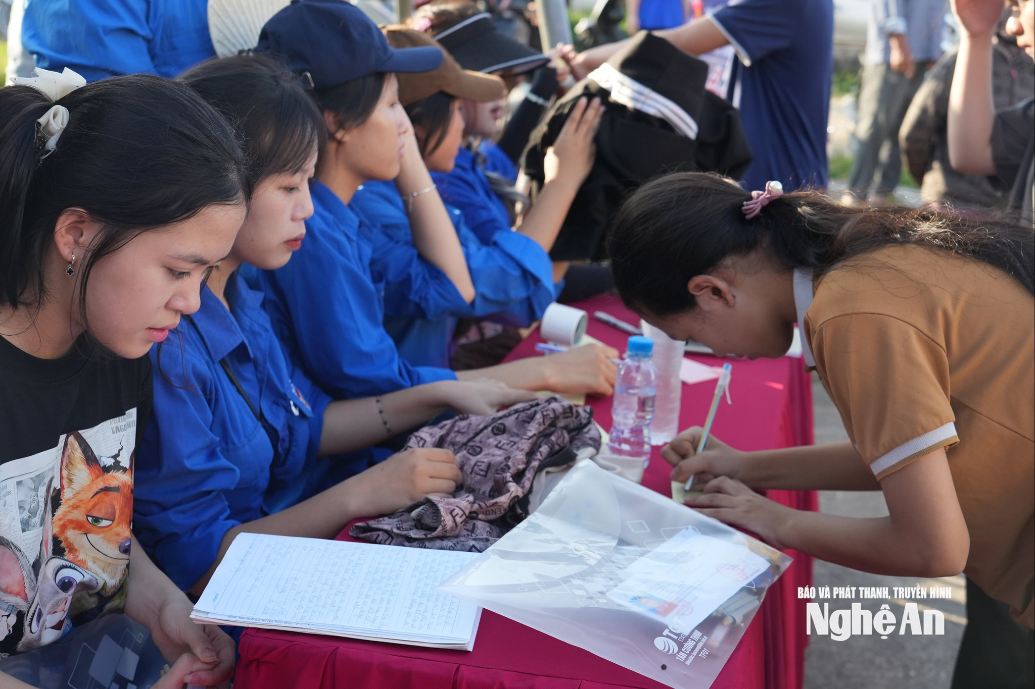 Trước khi bước vào phòng thi, đội thanh niên tình nguyện đã hỗ trợ thí sinh giữ đồ, phát miễn phí nước, quạt mát. Ảnh: Mỹ