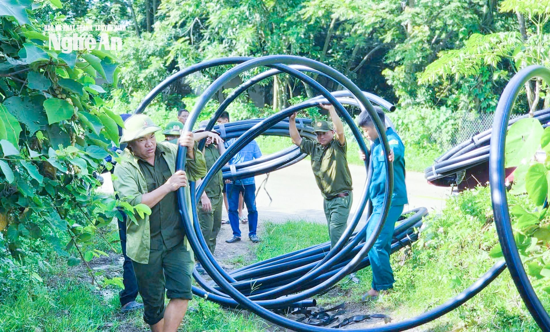 Cán bộ, công chức và lực lượng vũ trang xã Nghĩa Lâm vận chuyển và lắp đặt đường ống, đưa nước về các trường học để dạy bơi cho học sinh. Ảnh: Mai Hoa