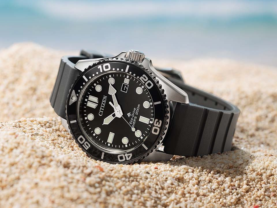 Citizen Promaster Marine BN0266-07E với mặt số đen, niềng đen và dây đen đặt trên cát.