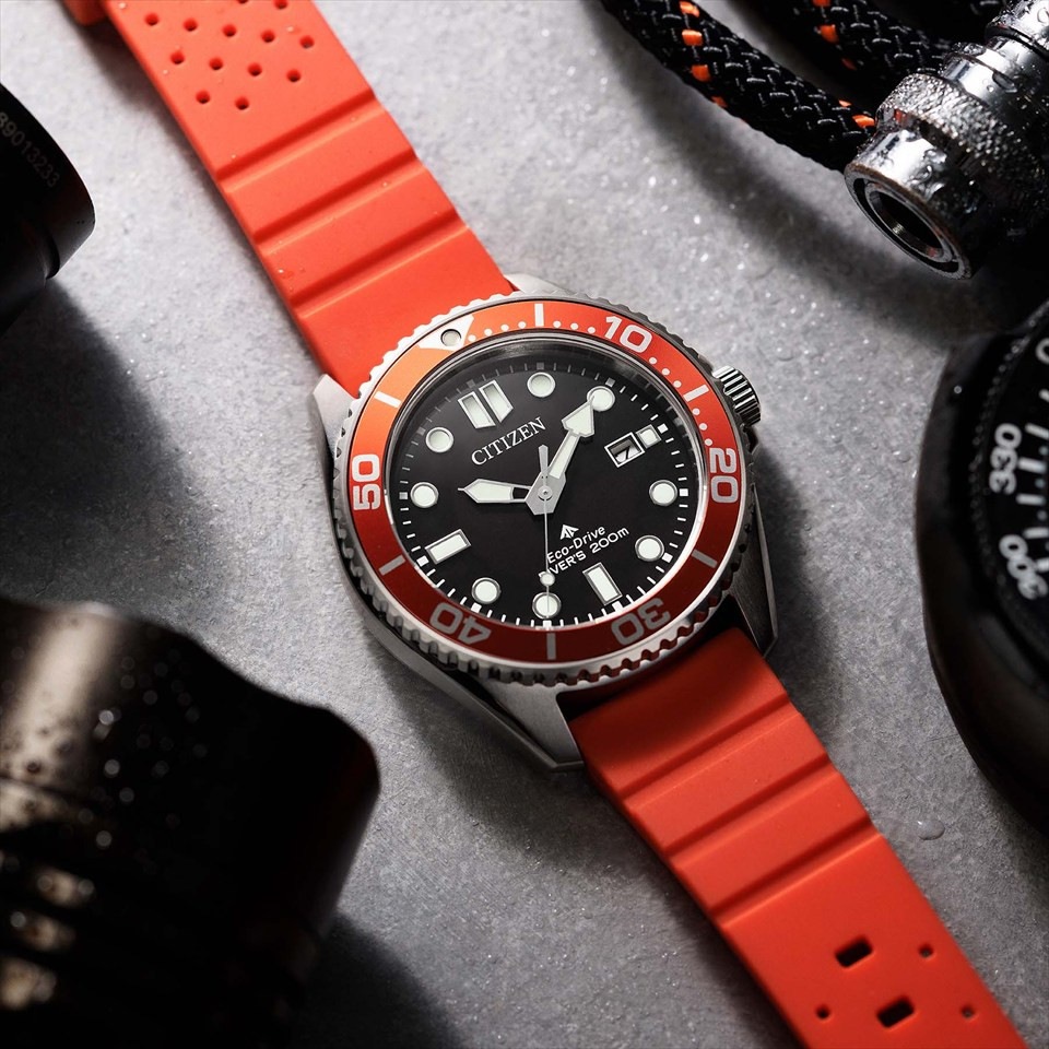 Đồng hồ lặn Citizen Promaster Marine BN0268-01E với mặt số đen, niềng cam và dây đeo cam chụp trên bề mặt có vân.