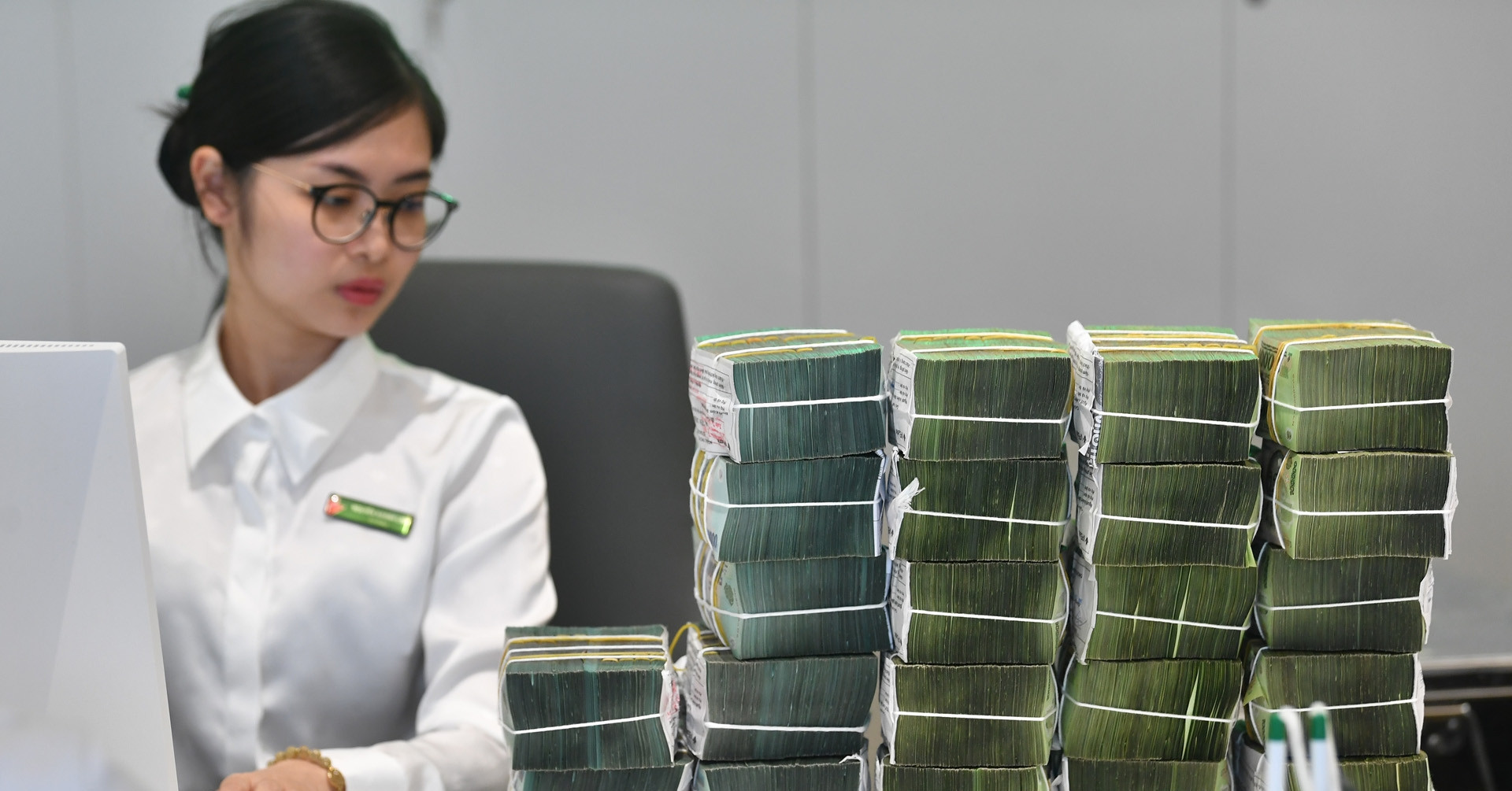 Giao dịch viên ngân hàng đang hỗ trợ khách hàng gửi tiết kiệm tại quầy