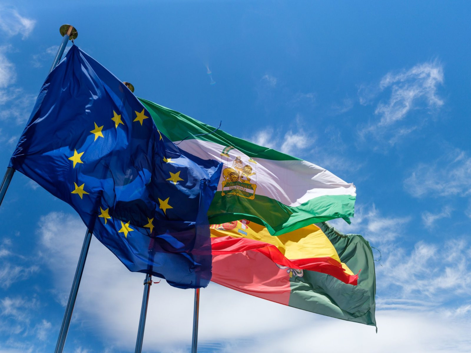 Flags of the European Union fly against a blue sky
