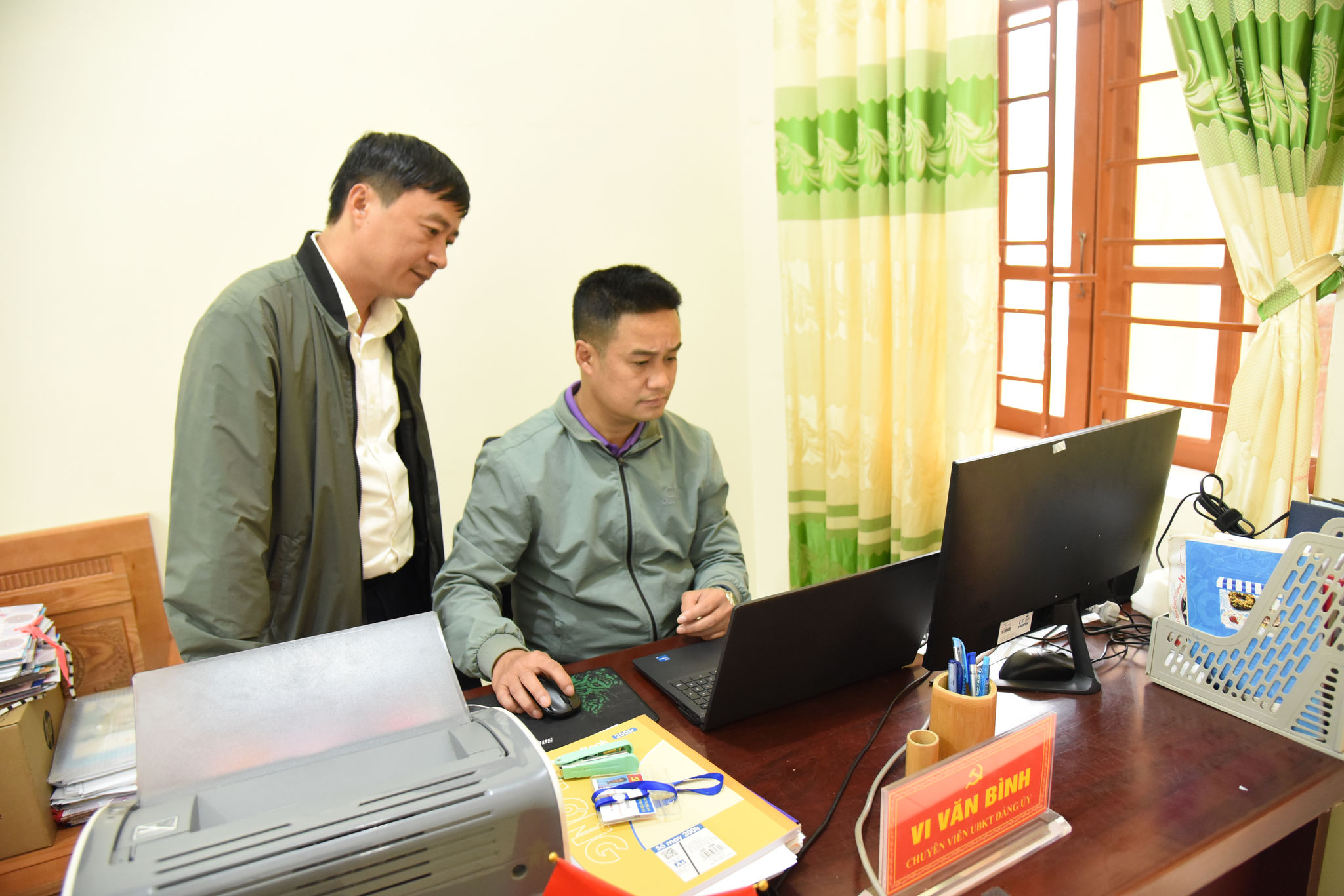 Ông Lê Thành Đô - Phó Bí thư Thường trực Đảng uỷ xã Bình Chuẩn (bên trái) hướng dẫn cán bộ các phòng ban thực hiện nhiệm qua hệ thống dịch vụ công (1)