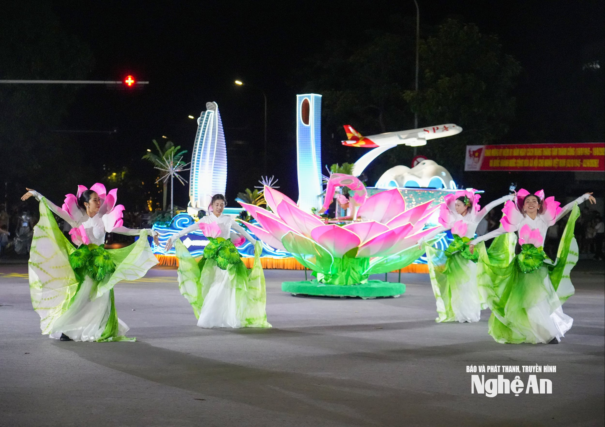 các vũ công trong trang phục trắng, hồng và xanh lá tạo nên những lớp chuyển động mềm mại, gợi hình ảnh một đầm sen giữa không gian đường phố.
