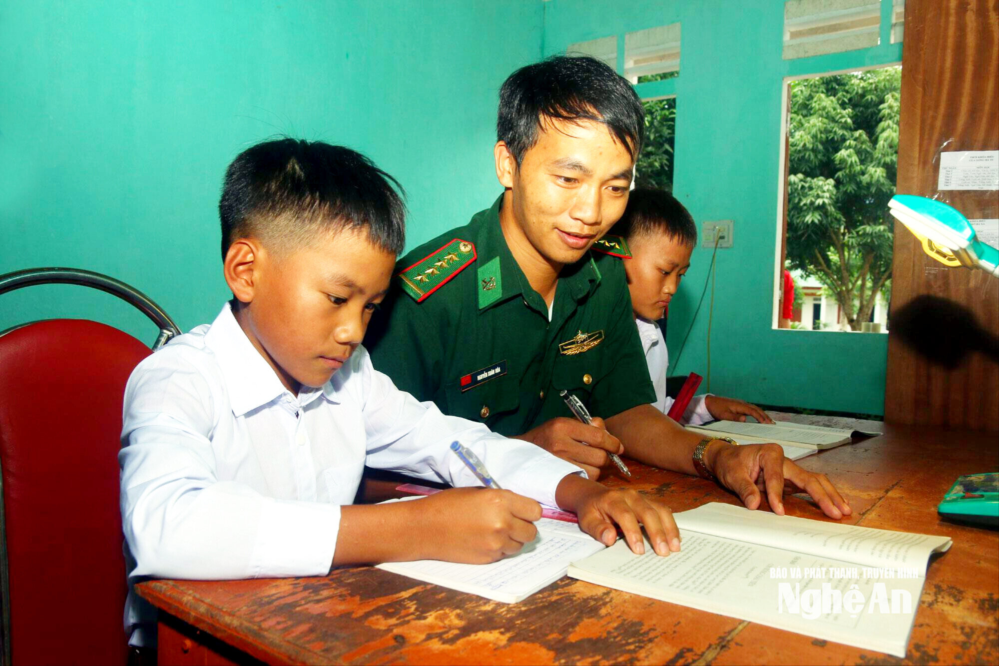 Cán bộ Đồn biên phòng Nậm Càn hướng dẫn hai con nuôi Thò Bá Cha và Xồng Bá Tu học bài. Ảnh tư liệu Đào Thọ