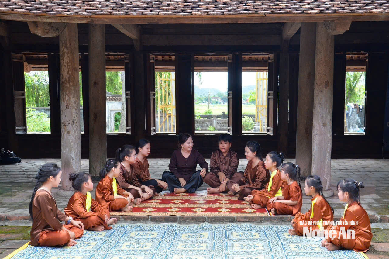 Nghệ nhân Nhân dân Hồng Vân truyền dạy dân ca ví, giặm cho các em nhỏ tại sân đình làng. Ảnh NVCC